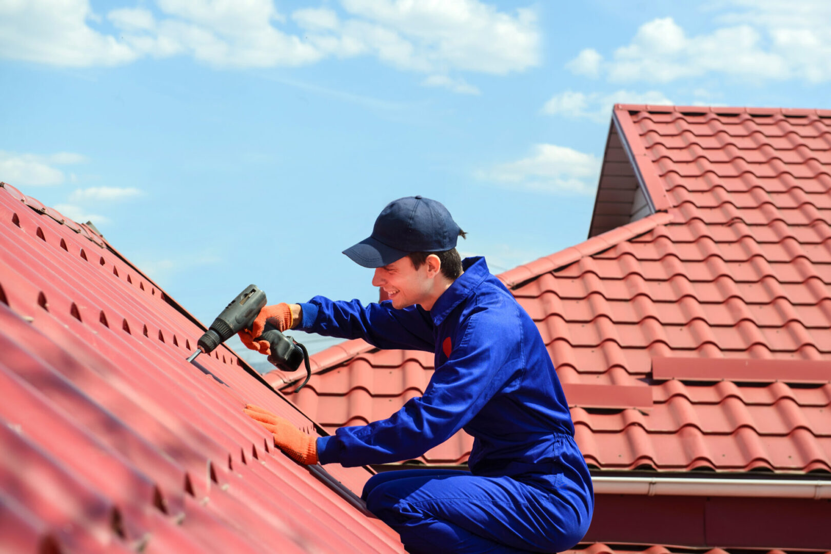 Roofer works on residential roof tiles with a power drill.