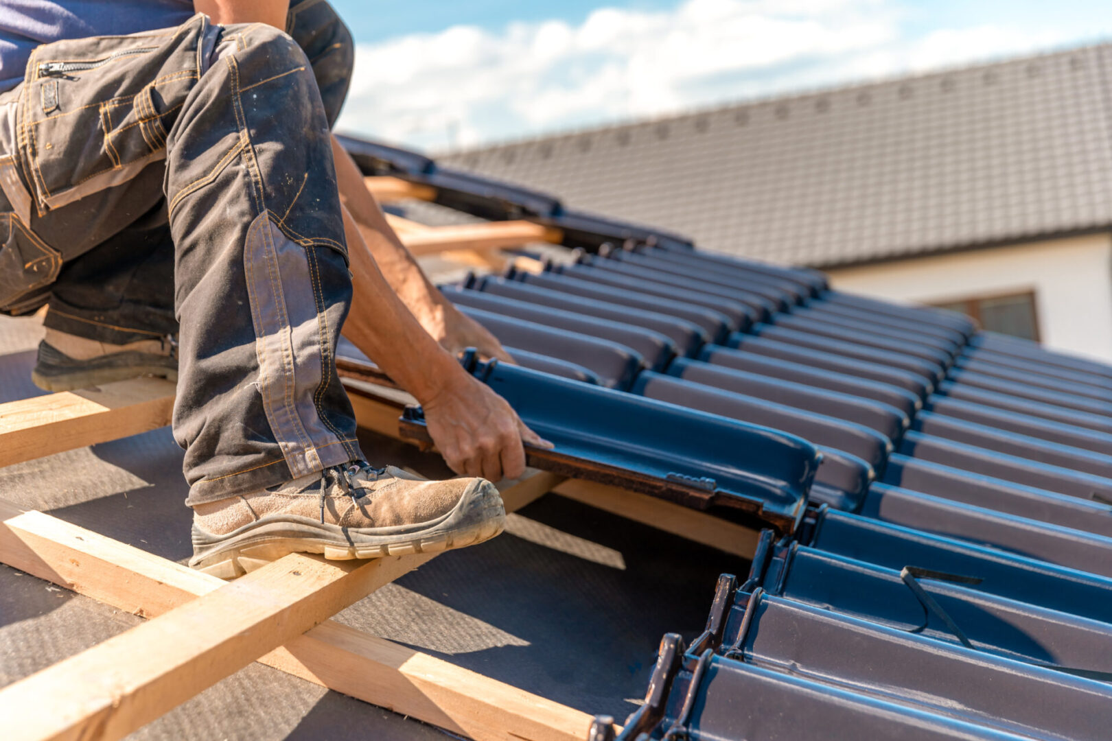 Roofer installs ceramic tile on a wooden frame of the new roof