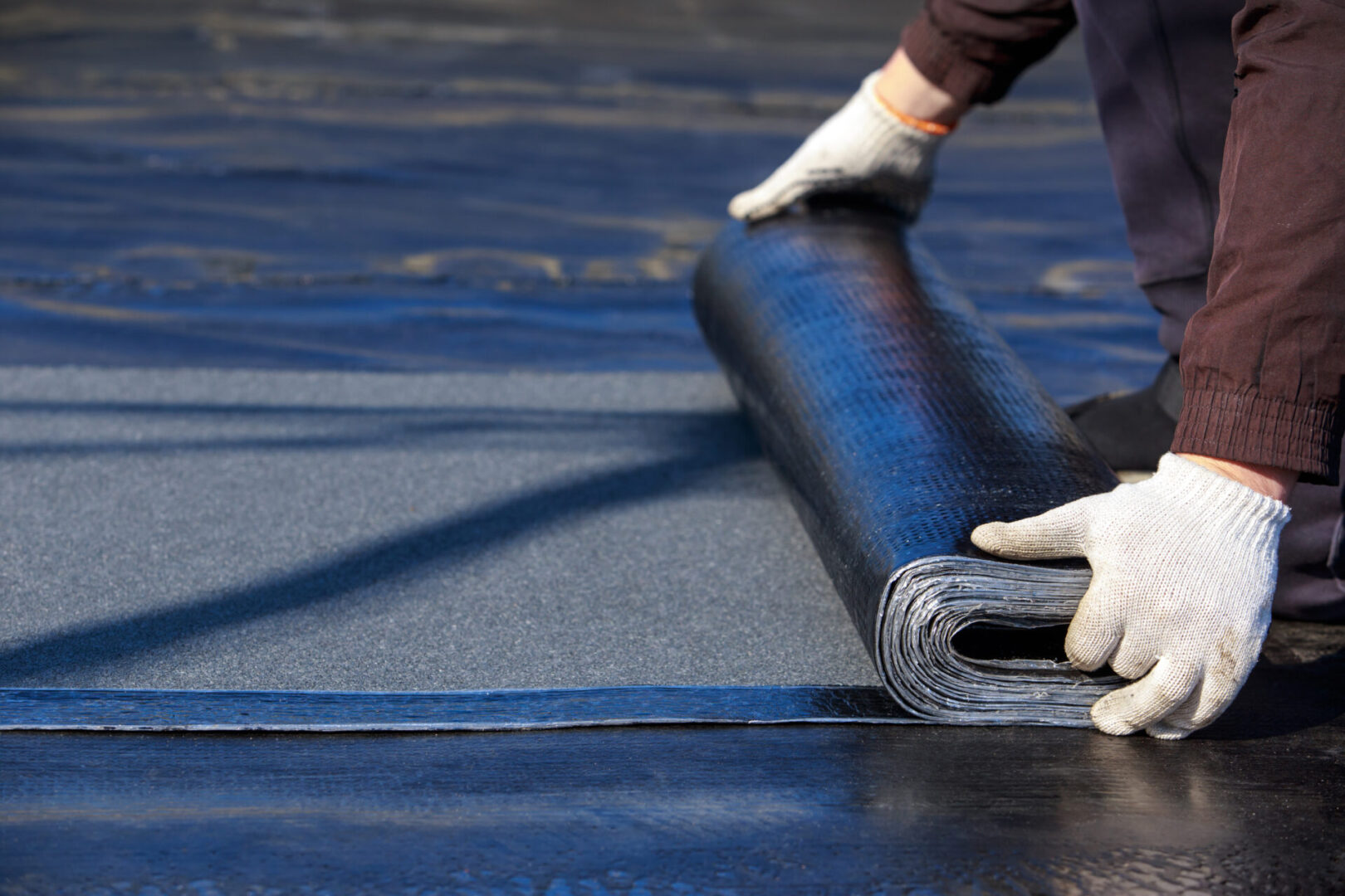 Worker unrolling roofing material