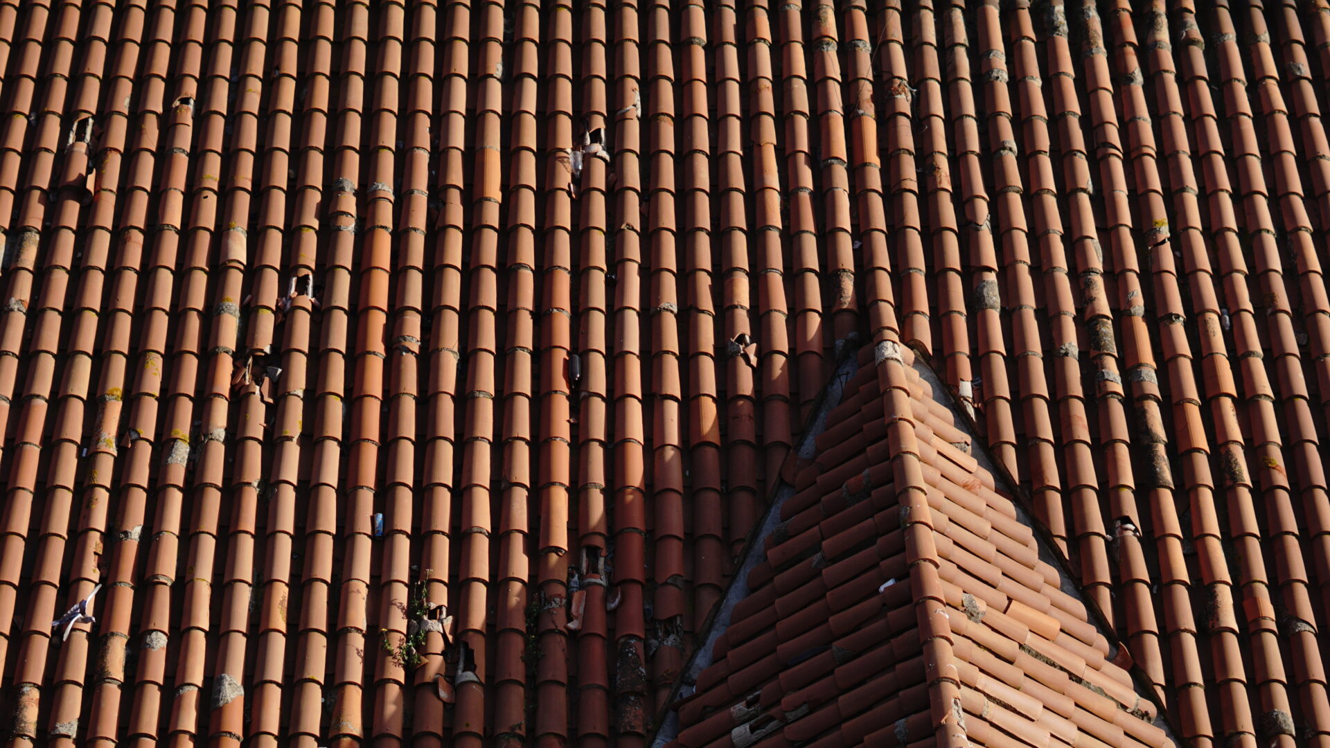 Aerial view of red tile roof with broken tiles