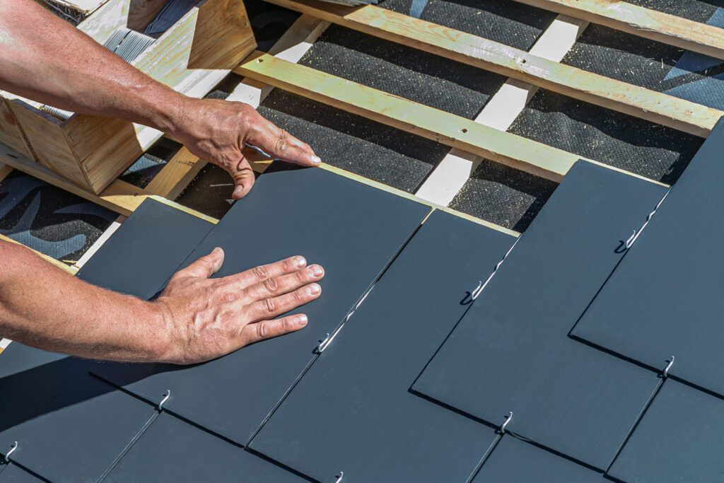 Professional installing slate shingles on roof