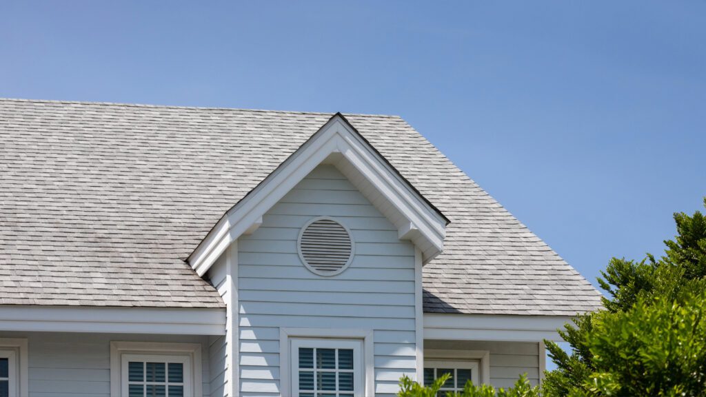A light gray shingle roof in a home with blue siding and white trim