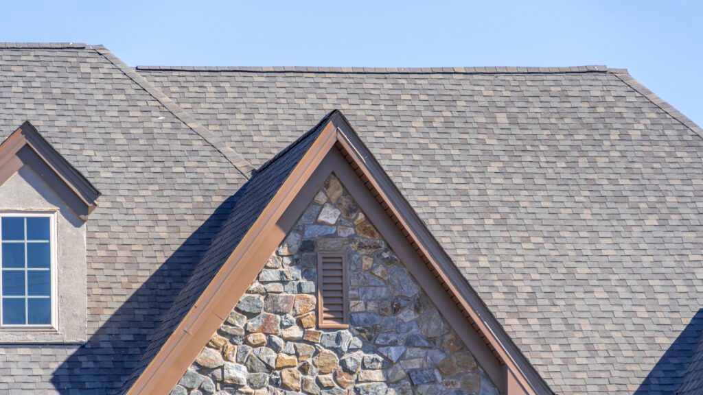 A light gray residential roof on a home with stone siding